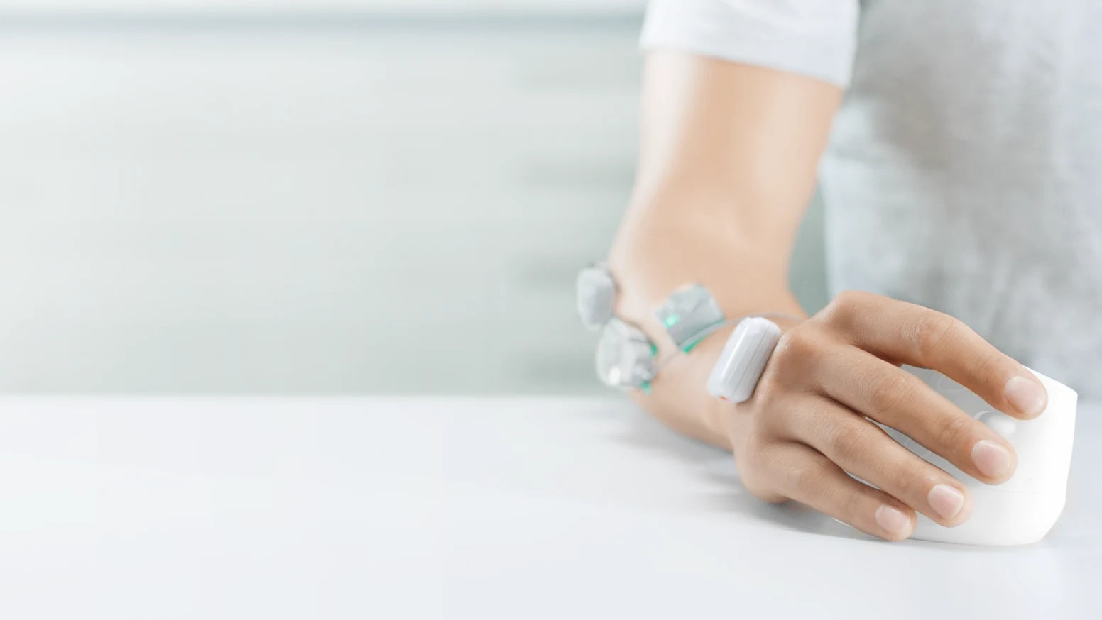 Hand mit ergonomischer Maus und EMG-Sensoren am Unterarm für VR-Tracking.