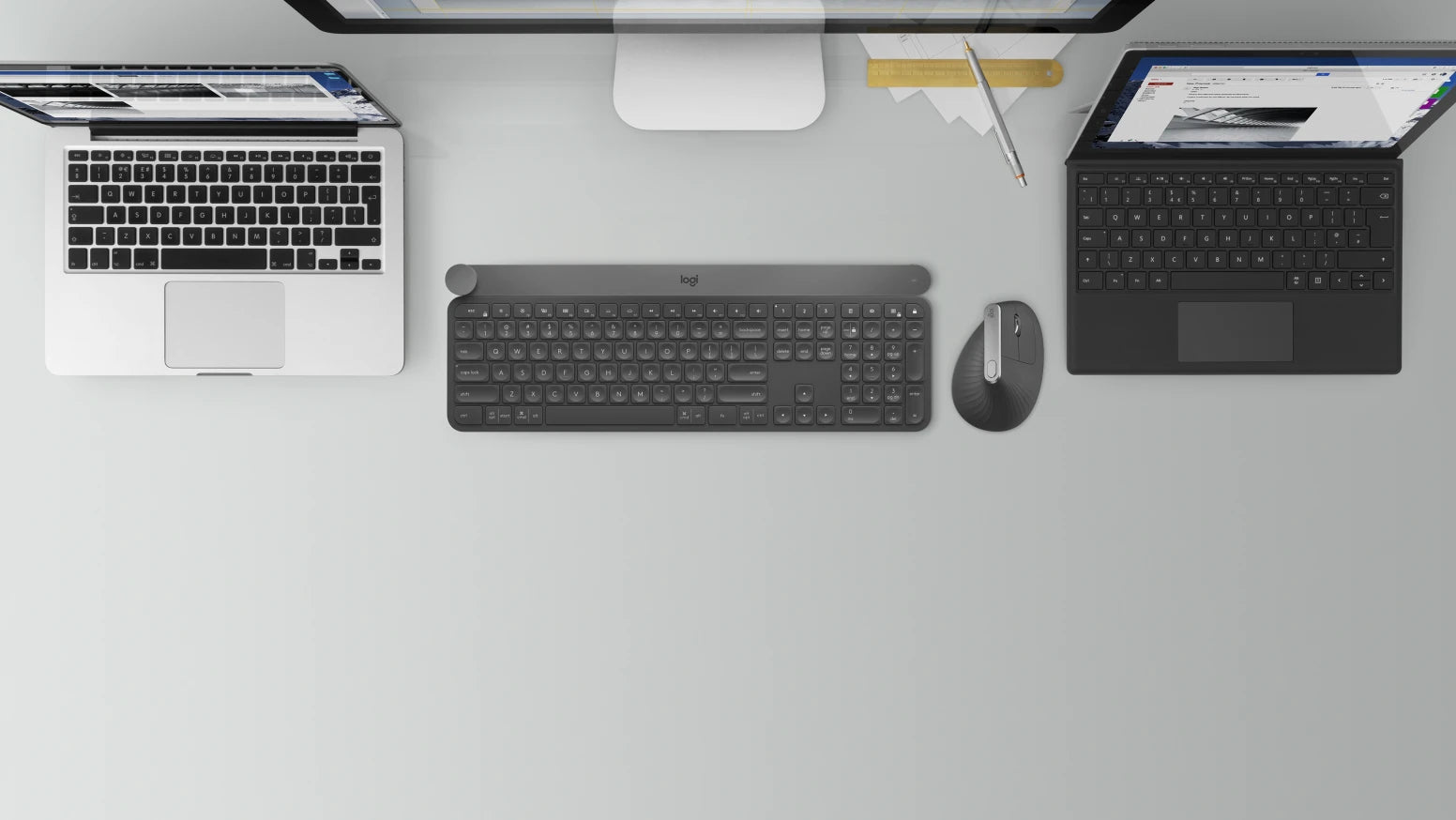 Moderner Arbeitsplatz von oben mit zwei Laptops, externer Logitech-Tastatur und Maus auf hellem Schreibtisch.