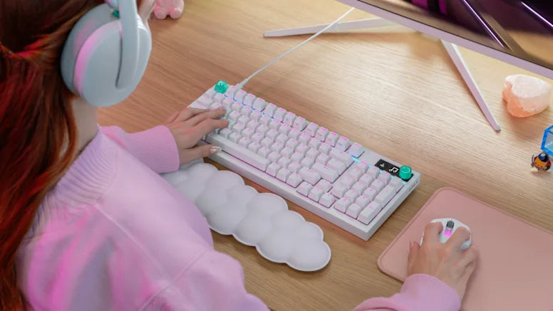 Frau nutzt weiße Gaming-Tastatur mit RGB-Beleuchtung und Gaming-Maus an hellem Holztisch