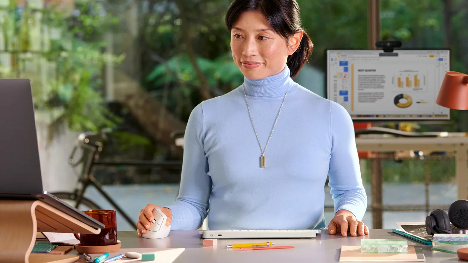 Frau arbeitet an einem modernen Laptop mit ergonomischer Maus und Tastatur am Schreibtisch
